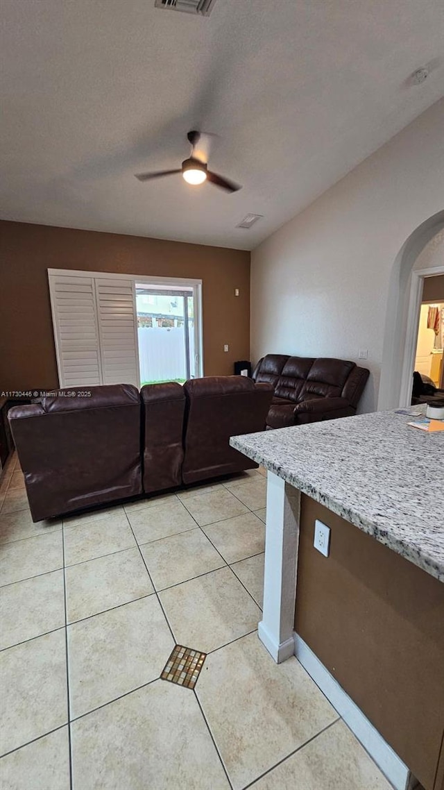 kitchen with light stone counters, a textured ceiling, light tile patterned floors, and ceiling fan