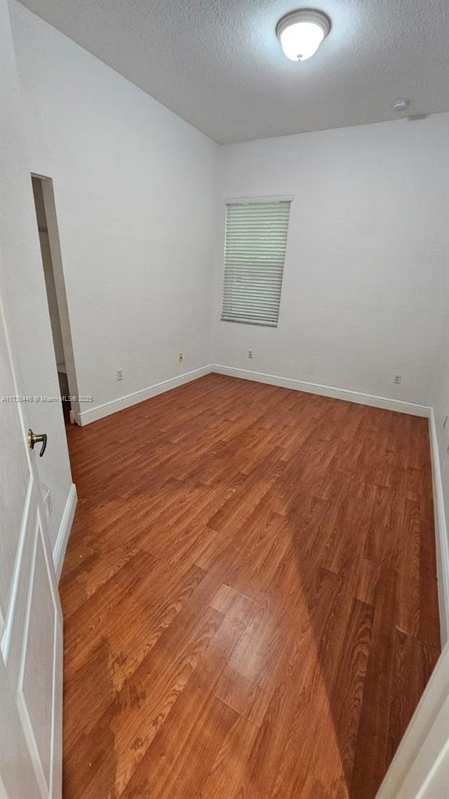 empty room featuring a textured ceiling and wood-type flooring