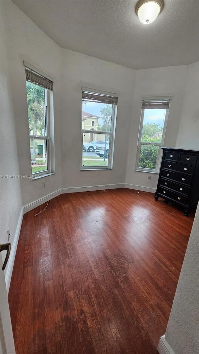 spare room featuring dark wood-type flooring and a textured ceiling