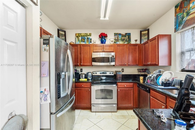 kitchen with dark stone countertops, light tile patterned floors, and appliances with stainless steel finishes