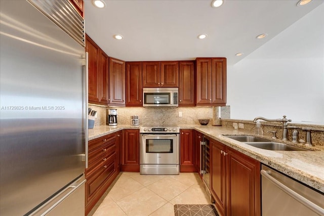 kitchen featuring appliances with stainless steel finishes, sink, decorative backsplash, light tile patterned floors, and light stone countertops