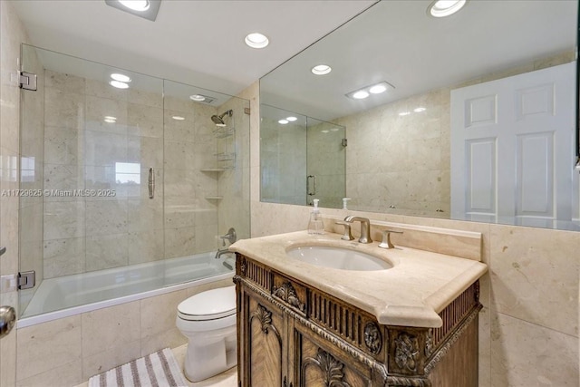 full bathroom with vanity, tile walls, shower / bath combination with glass door, and toilet