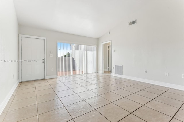 tiled empty room featuring vaulted ceiling