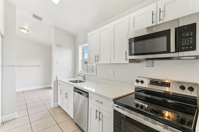 kitchen featuring white cabinets, light tile patterned floors, appliances with stainless steel finishes, and sink