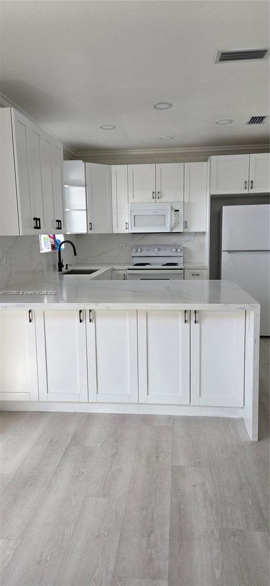 kitchen with sink, white cabinets, tasteful backsplash, white appliances, and light hardwood / wood-style floors