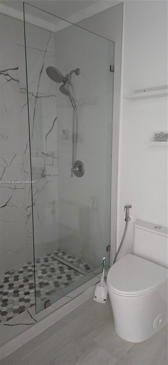 bathroom featuring tiled shower and toilet