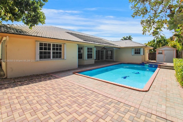 view of swimming pool with french doors, an outbuilding, a shed, and a patio area