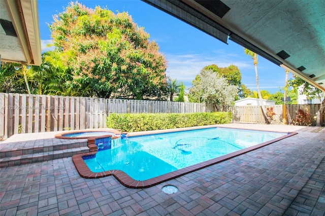 view of swimming pool featuring a patio area, a fenced backyard, and a pool with connected hot tub