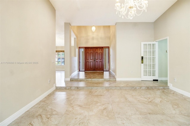 foyer entrance with a chandelier, a towering ceiling, and baseboards