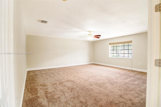 carpeted empty room featuring a textured ceiling, baseboards, a ceiling fan, and visible vents