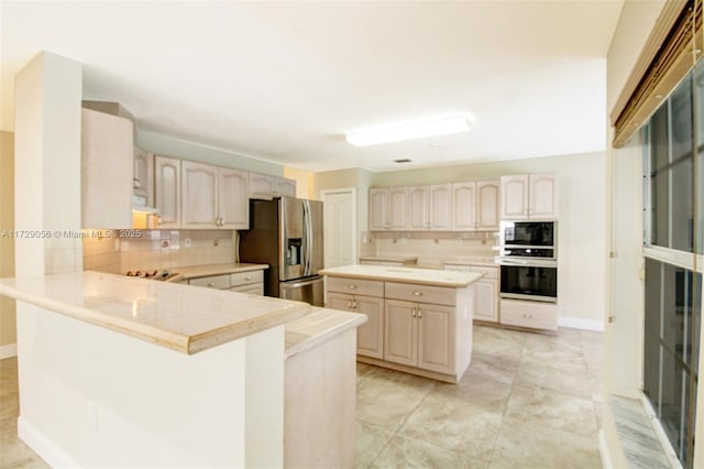 kitchen featuring a peninsula, wall oven, decorative backsplash, and stainless steel fridge