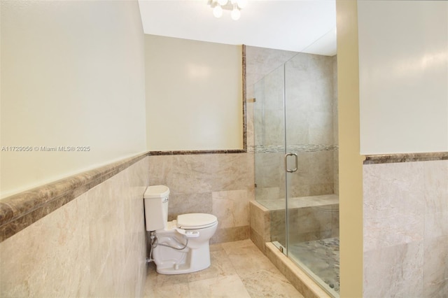 full bathroom featuring toilet, tile walls, a stall shower, and wainscoting