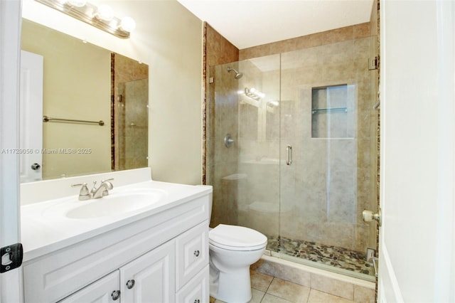 bathroom with toilet, vanity, a stall shower, and tile patterned flooring