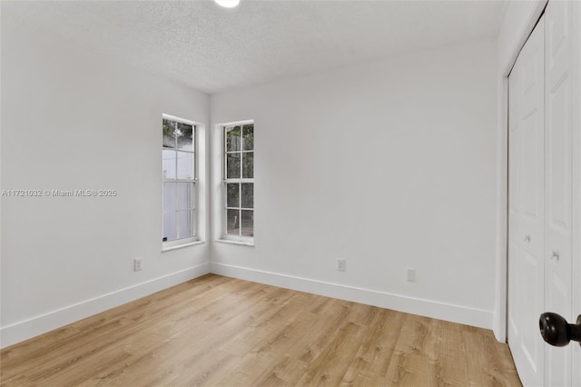 unfurnished room with light hardwood / wood-style flooring and a textured ceiling