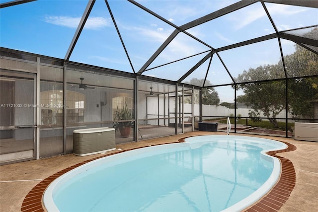 view of swimming pool with ceiling fan, glass enclosure, and a patio area