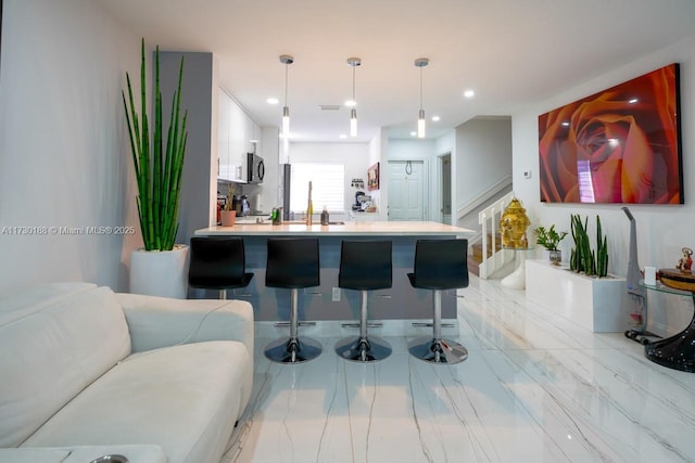 kitchen featuring kitchen peninsula, sink, a kitchen bar, and hanging light fixtures