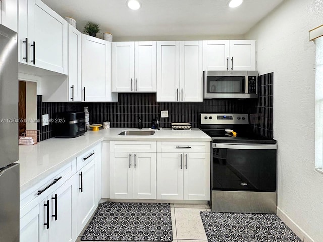 kitchen featuring sink, stainless steel appliances, white cabinetry, and tasteful backsplash