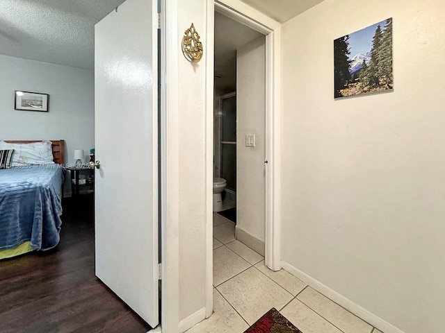 corridor with a textured ceiling and light tile patterned floors