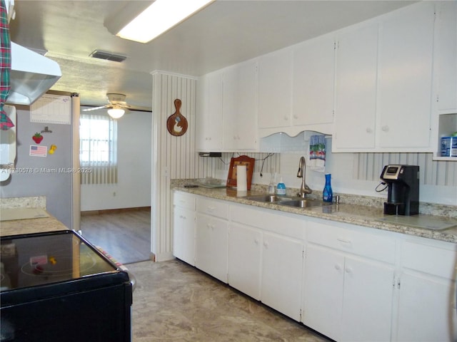 kitchen featuring sink, white cabinets, stainless steel refrigerator, and black / electric stove