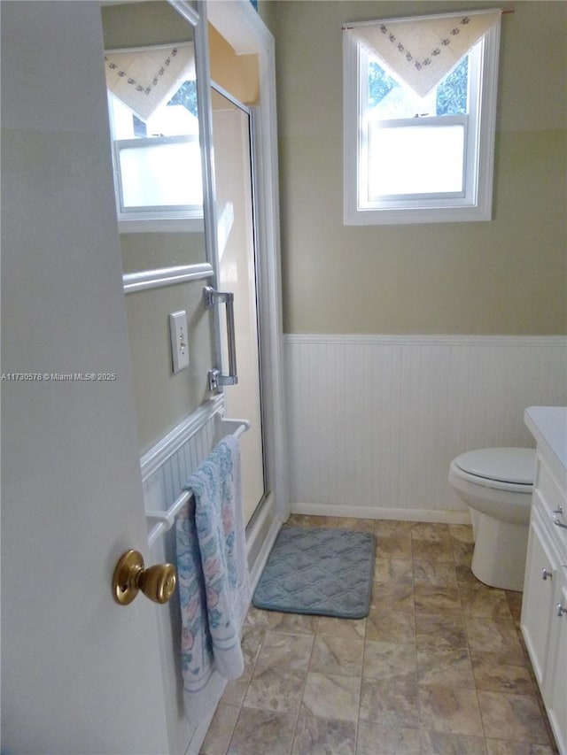 bathroom featuring a shower with door, vanity, and toilet