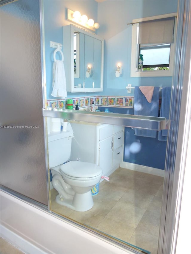 full bathroom with bath / shower combo with glass door, vanity, and toilet