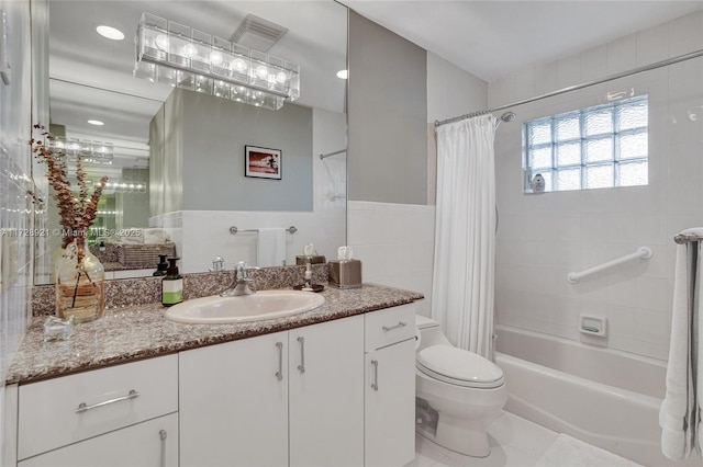 full bathroom with shower / tub combo with curtain, tile patterned floors, toilet, tile walls, and vanity