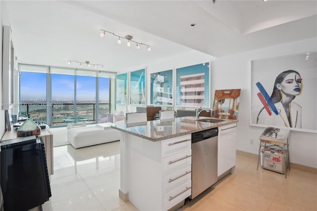 kitchen with sink, light tile patterned floors, white cabinetry, light stone counters, and stainless steel dishwasher