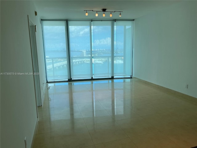 tiled spare room featuring track lighting and floor to ceiling windows