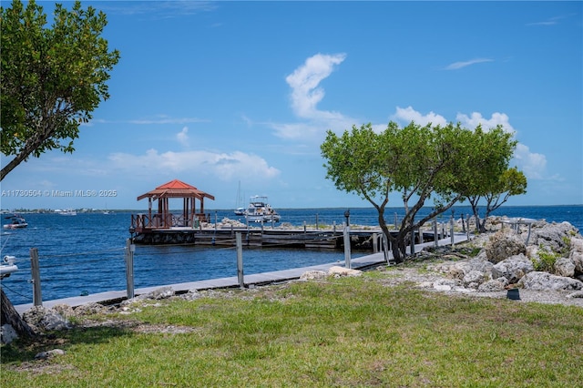 view of dock with a gazebo, a yard, and a water view