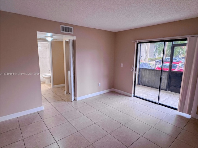 tiled empty room with a textured ceiling