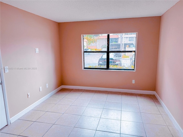 spare room with light tile patterned flooring and a textured ceiling