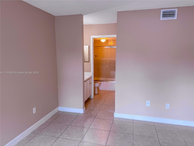 unfurnished room featuring light tile patterned floors and a textured ceiling