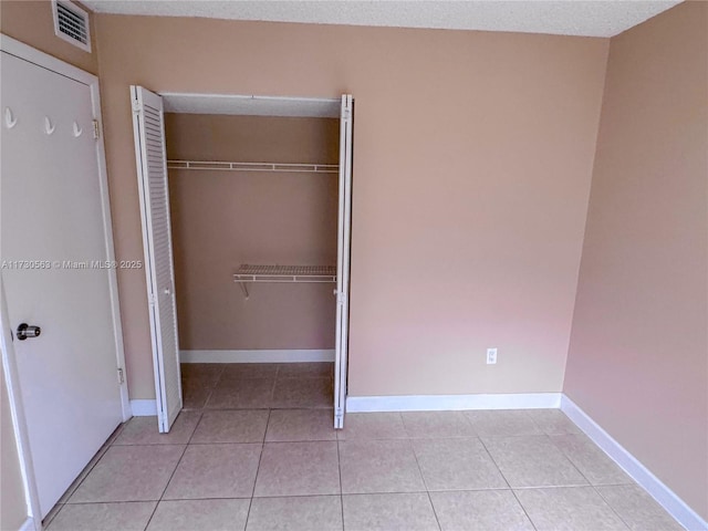 unfurnished bedroom with a textured ceiling, a closet, and light tile patterned floors