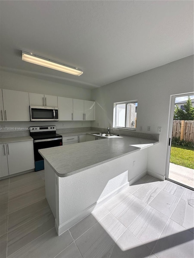 kitchen featuring sink, white cabinets, appliances with stainless steel finishes, and kitchen peninsula