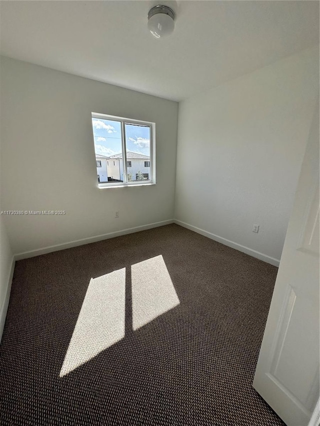 spare room featuring dark carpet