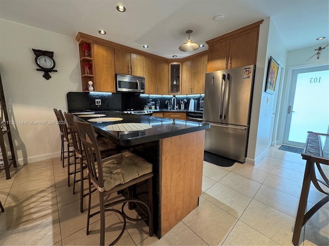 kitchen featuring stainless steel appliances, plenty of natural light, a kitchen breakfast bar, backsplash, and light tile patterned flooring