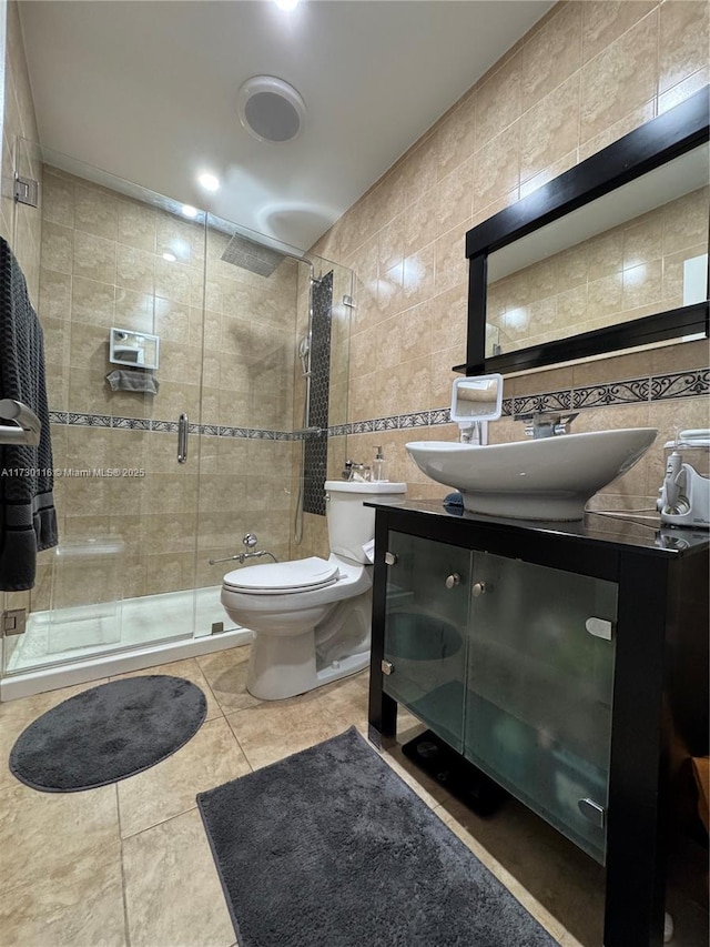 bathroom featuring tile patterned flooring, tile walls, toilet, walk in shower, and vanity