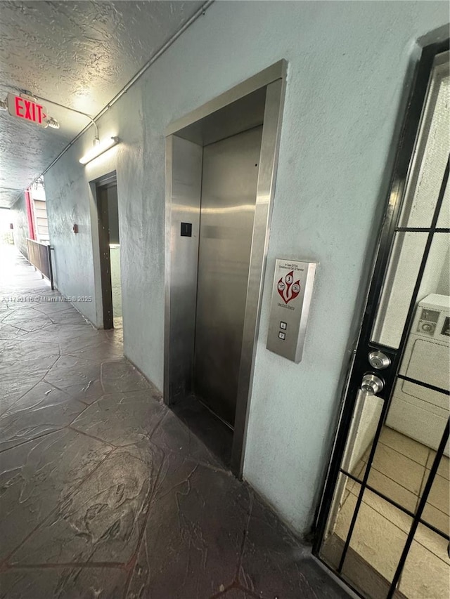 corridor featuring elevator and a textured ceiling