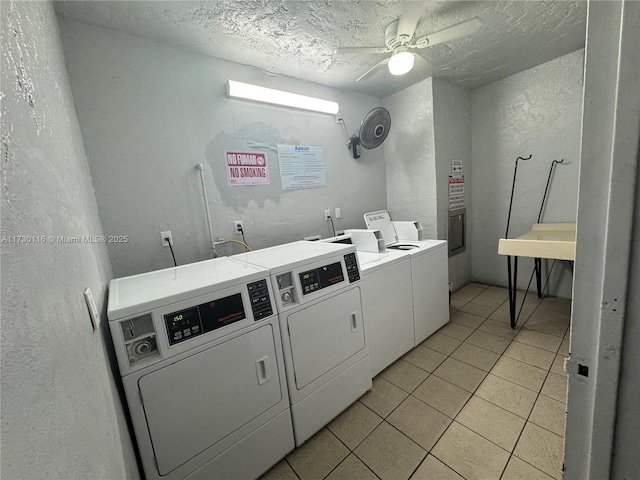 clothes washing area featuring washing machine and clothes dryer, ceiling fan, a textured ceiling, and light tile patterned flooring