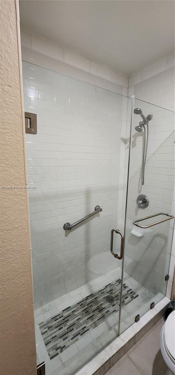 bathroom featuring a shower with door and toilet