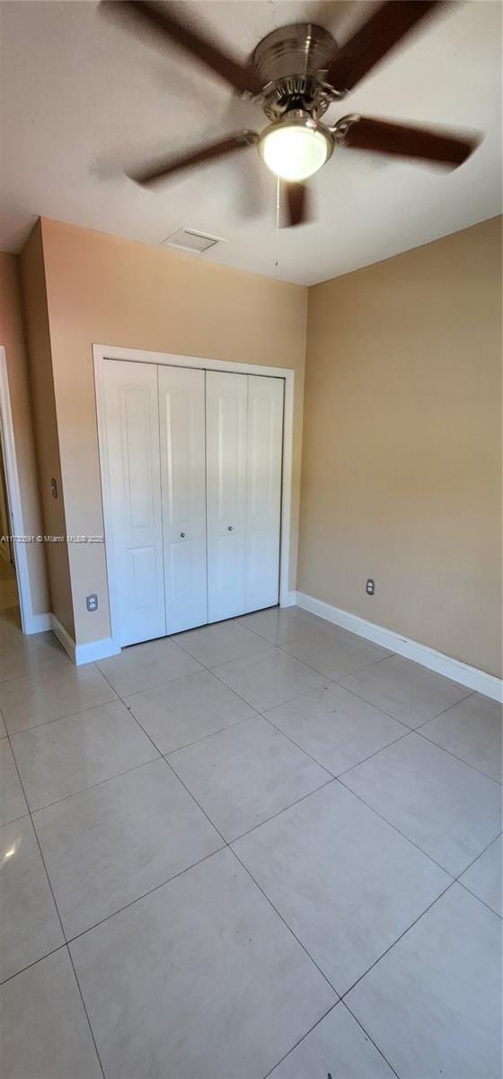 unfurnished bedroom featuring light tile patterned flooring, ceiling fan, and a closet