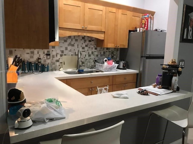 kitchen featuring sink, stainless steel fridge, and backsplash