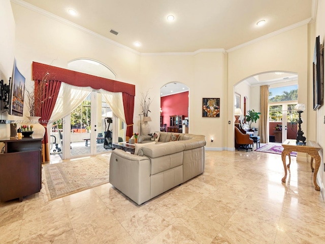 living room featuring a towering ceiling, ornamental molding, and french doors