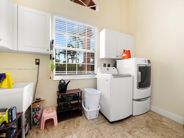 clothes washing area with washer and clothes dryer and cabinets