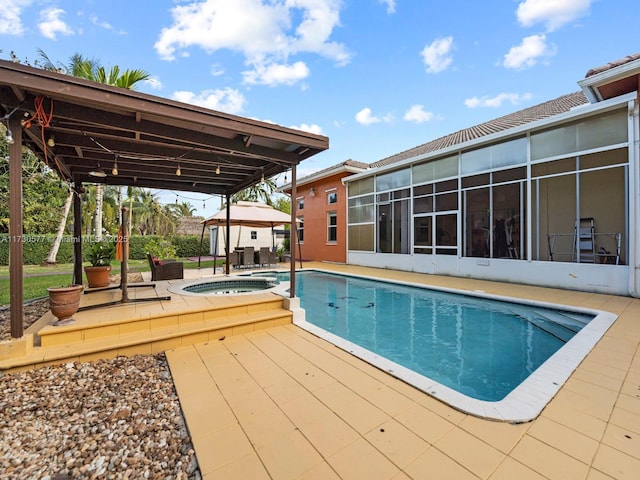 view of swimming pool featuring a patio area, a sunroom, and an in ground hot tub