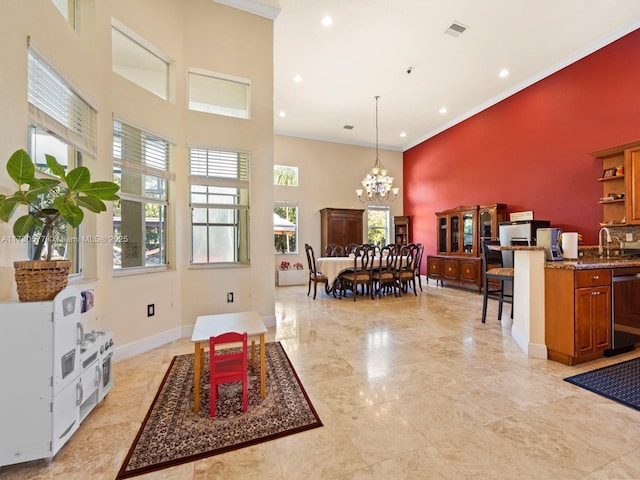 living room with an inviting chandelier, a towering ceiling, crown molding, and sink