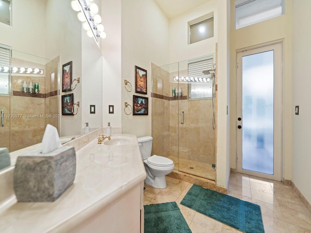 bathroom with a towering ceiling, vanity, toilet, and a shower with shower door