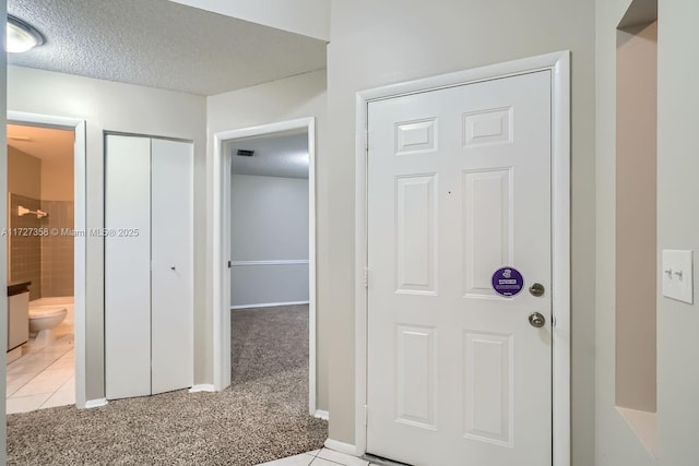 carpeted foyer featuring a textured ceiling