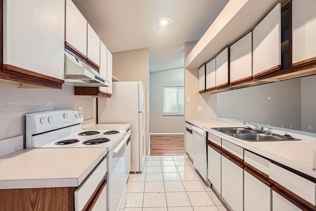 kitchen with white appliances, white cabinets, lofted ceiling, sink, and light tile patterned flooring