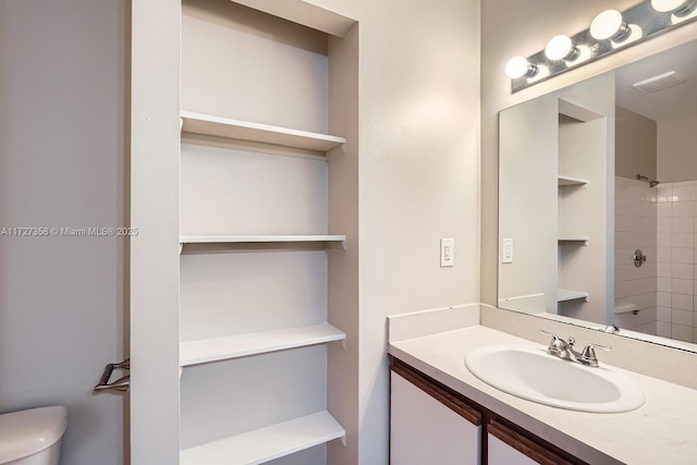 bathroom featuring vanity, toilet, and tiled shower